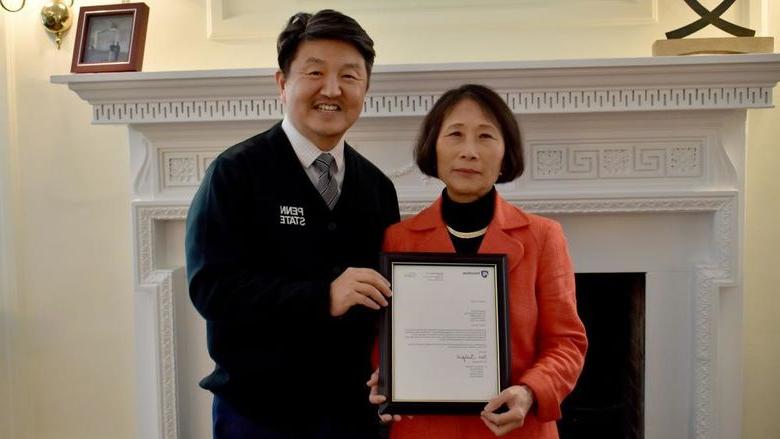 Penn State DuBois chancellor and chief academic officer Jungwoo Ryoo, right, presents Pingjuan Werner with a framed copy of the letter certifying her as a distinguished professor, the highest professorial distinction at the University